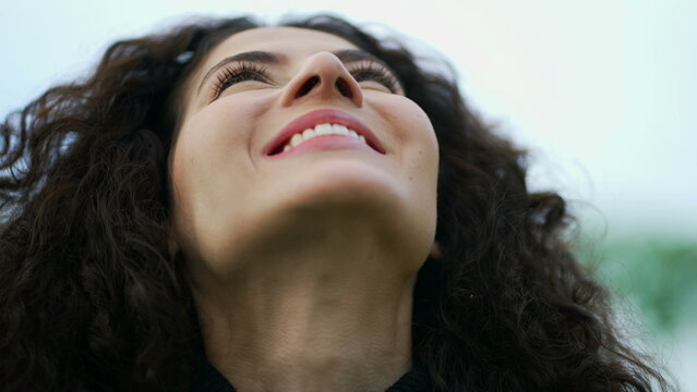 Woman raises head to sky in contemplation. Smiling spiritual person looking up