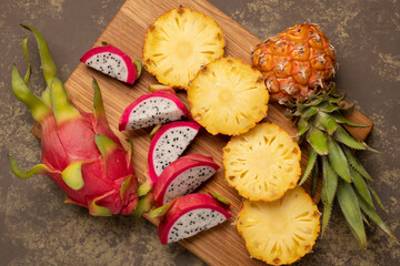 Sliced ​​ripe dragon fruit and pineapple on a kitchen board with a knife. Top view.