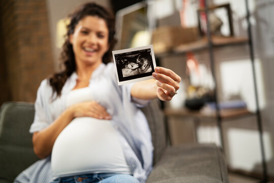 Pregnant woman with ultrasound photo. Beautiful pregnant woman enjoy at home.