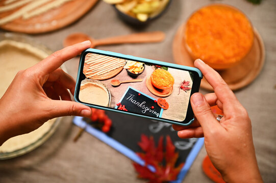 Close-up of a food blogger using mobile phone in live view mode, taking photo of fresh raw ingredients for making a homemade American classic pie, for a Thanksgiving dinner. Autumn holidays. Halloween