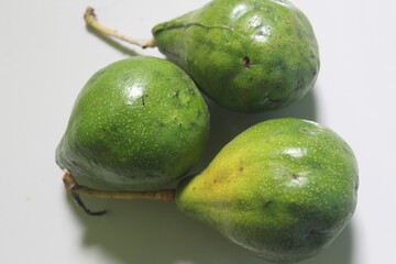 three unripe avocados on the floor