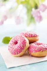 Rosa Doughnuts vor frühlingshaftem Tulpenstrauß