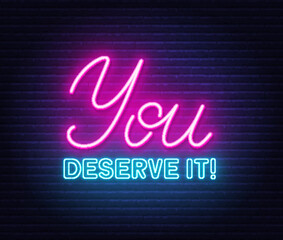 You Deserve It neon quote on a brick wall.