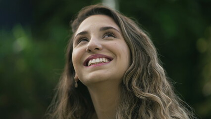 Naklejka premium Happy woman closeup face looking up at sky smiling. One hopeful hispanic 20s adult girl