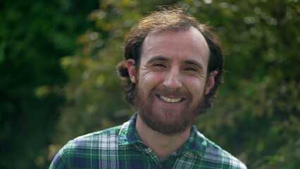 Happy man closeup face. Portrait of a redhead casual male person standing outdoors in nature