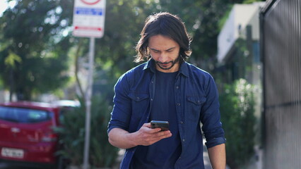 Man holding smartphone walking in urban city street. Tracking motion shot of a person checking phone going forward