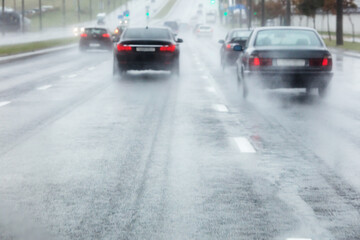 cars rides in wet road with water spraying from the wheels. blurred view through windshield.