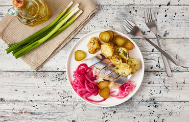 Herring with baked potato, onions and pickled cucumber, flatlay