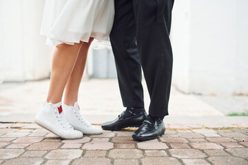Close up view of legs on the ground. Beautiful bride with his fiance is celebrating wedding outdoors