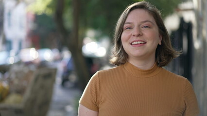 Portrait of a happy young woman walking in city sidewalk. Millennial girl in 20s walks forward feeling confidence