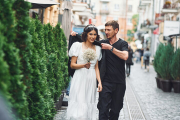 Walking by a street. Beautiful bride with his fiance is celebrating wedding outdoors