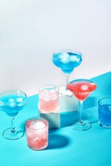 Multi-colored cocktails in glasses of different shapes on colored backgrounds with hard shadows