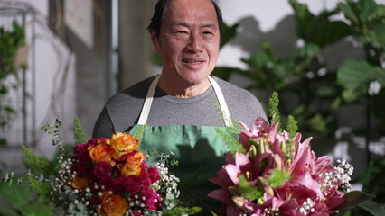 One Happy Asian Florist professional holding two bouquet of flowers for client. Portrait of middle age entrepreneur of small business