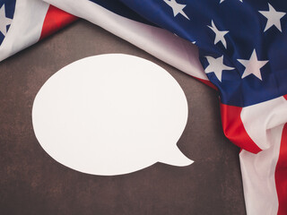 Top view of the American flag with a blank white speech bubble on a table