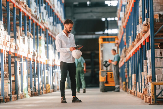 Using tablet to check the products. Storage worker is in the warehouse