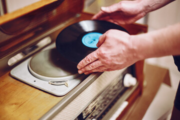 Vinyl record, spinning on turntable, Vintage record player with radio 60's. Mens hands putting...