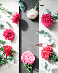 Red, pink and white asters along with dry eucalyptus branches are on a white wooden background. Autumn background with copy space, thanksgiving day concept.