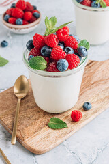 Delicious italian dessert panna cotta with fresh raspberry, blueberries and mint on gray marble background