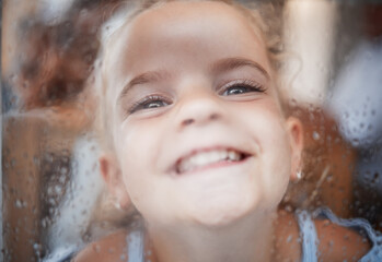 Happy funny girl, face on window with flat nose on rainy glass and comic portrait at home. Young kid play joke, child alone with big smile and laughing crazy humor closeup in San Francisco winter