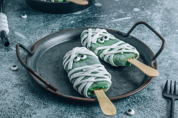 Fun Halloween monsters popsicle. Happy Holiday. Green chocolate popsicles with mastic bandages