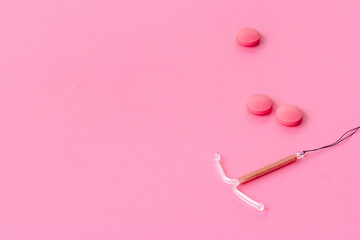 Contraception concept. T-shaped intrauterine contraceptive with medicine pills