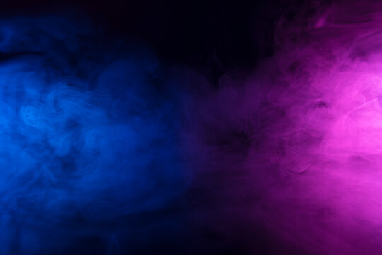 Colorful smoke clouds in blue and pink neon light swirling on empty scene dark background with reflection