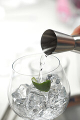 Pour gin into a glass with a cocktail measurer