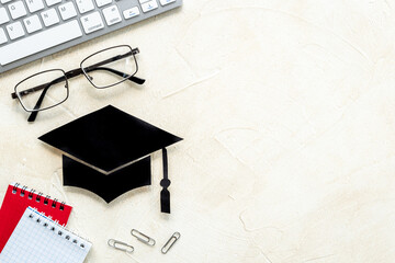 Graduation hat or academic cap on desk with students supplies