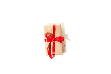 A gift wrapped in brown paper and tied red ribbon isolated on a white background with shadow. Top view
