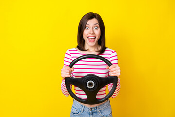 Photo of positive cheerful good mood girl with bob hairdo wear striped top staring hold steering wheel isolated on yellow color background