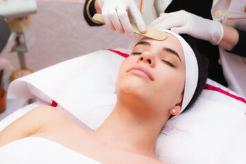 Young woman getting facial mask skin treatment in professional beauty salon