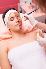 Young woman getting facial mask skin treatment in professional beauty salon