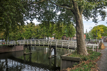 Fototapeta na wymiar Enkhuizen, The Netherlands, October 4, 2022: wooden pedestrian bridge across a canal in Boerenhoek neighbourhood
