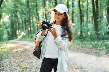 Using professional camera. Girl is in the forest at summer day time discovering new places