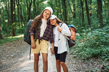 Front view. Two girls is in the forest having a leisure activity, discovering new places