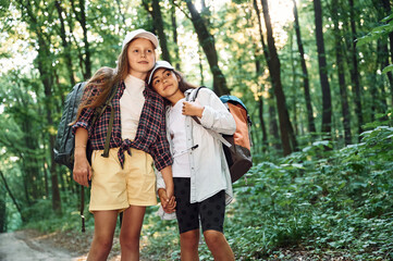 Front view. Two girls is in the forest having a leisure activity, discovering new places