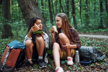 Sitting and eating. Two girls is in the forest having a leisure activity, discovering new places