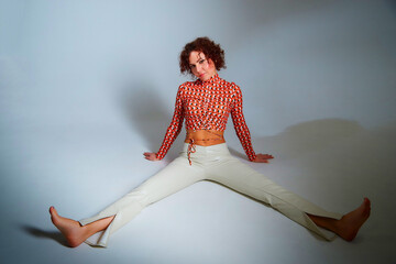 Portrait of beautiful slim young woman with short brunette hair in white trousers and red blouse in...