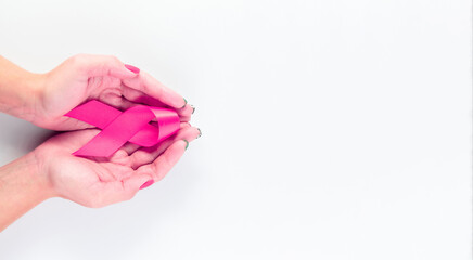 Cancer awareness. Health care symbol pink ribbon in woman hands on white background. Breast woman support concept. World cancer day.