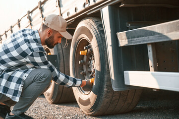 Testing the tires. Young truck driver is with his vehicle at daytime