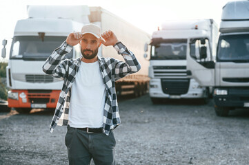 Front view. In cap. Young truck driver is with his vehicle at daytime © standret