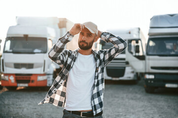 Front view. In cap. Young truck driver is with his vehicle at daytime © standret
