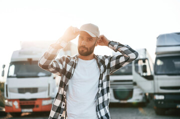 Standing against beautiful sunlight. Young truck driver is with his vehicle at daytime