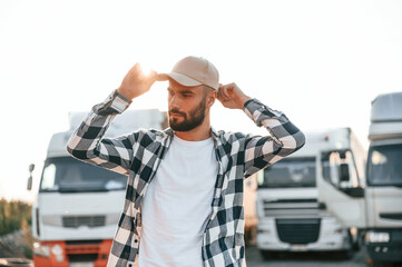Standing against beautiful sunlight. Young truck driver is with his vehicle at daytime © standret