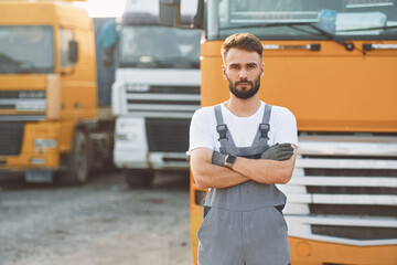 Standing and posing for the camera. Man in unifrom doing service for big truck vehicle