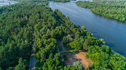 Fototapeta premium Aerial view summer forest and river in sunny day. Drone shot beautiful nature landscape, green trees