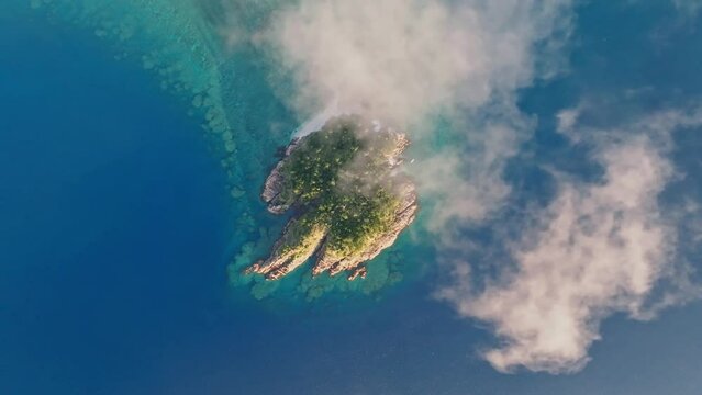 Aerial drone flight over Arkhurst Island, a small islet near Hayman Island, a luxury resort hotel in the Whitsunday Islands group near the Great Barrier Reef in Queensland, Australia. Layer of clouds.