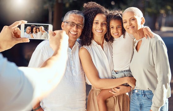 Phone, screen and happy family relax and smile while posing for a picture outdoors together, loving and embracing. Child, mother and grandparents bonding on a trip in nature, hug and enjoy summer