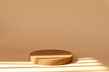 Round geometric wooden stand on brown background in rays of sunlight. Concept of 3d podium for presentation of cosmetic products.