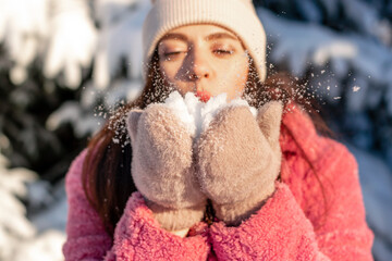 Young beautiful woman blowing snow off the hand.Winter, Christmas and Happy New Year concept.Selective focus, close up.